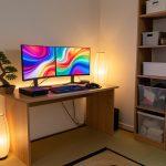 Coin gaming japonais soigneusement rangé dans une chambre d’adolescent, avec bureau en bois, écrans, console, manettes, lampe douce, bonsaï et rangements organisés.